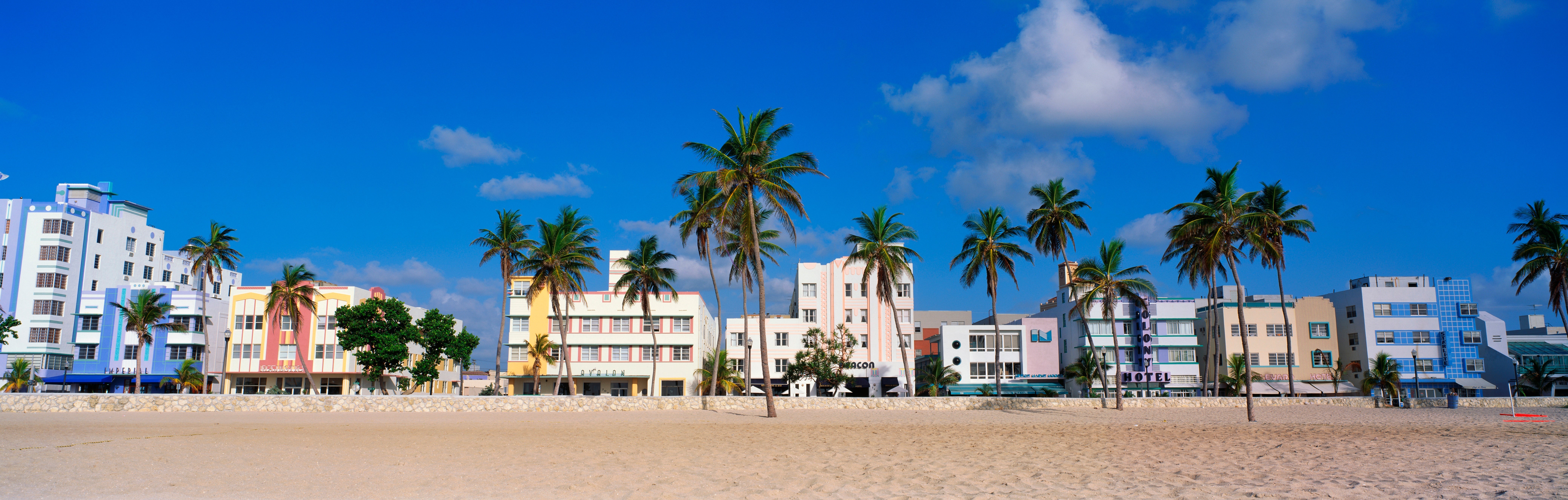 This is the art deco district of South Beach Miami. The buildings are painted in pastel colors surrounded by tropical palm trees.