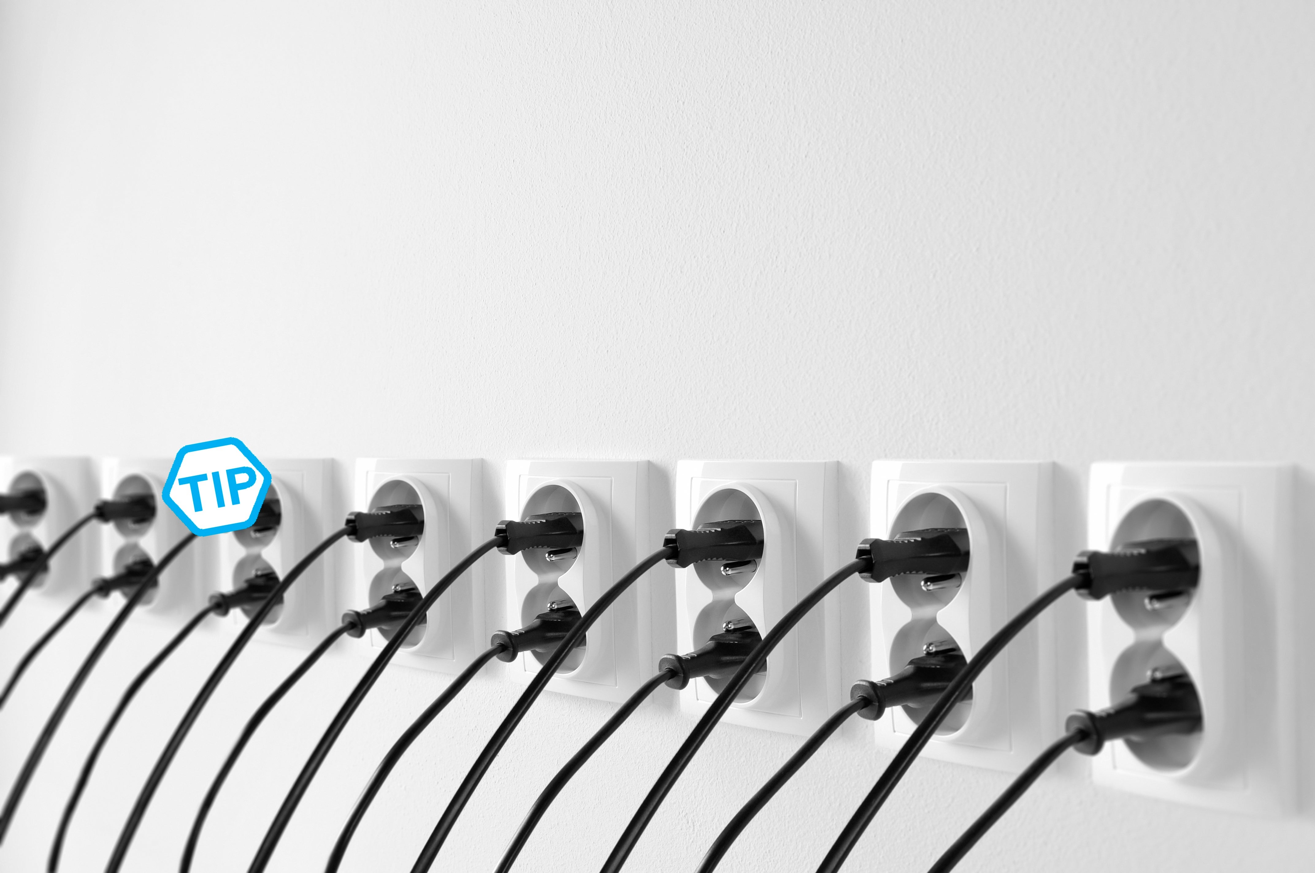 Group of wall outlets with black plugs, cables stucked in