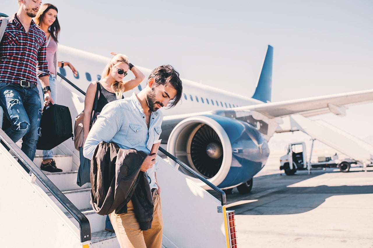 Four young people disembarking the airplane.