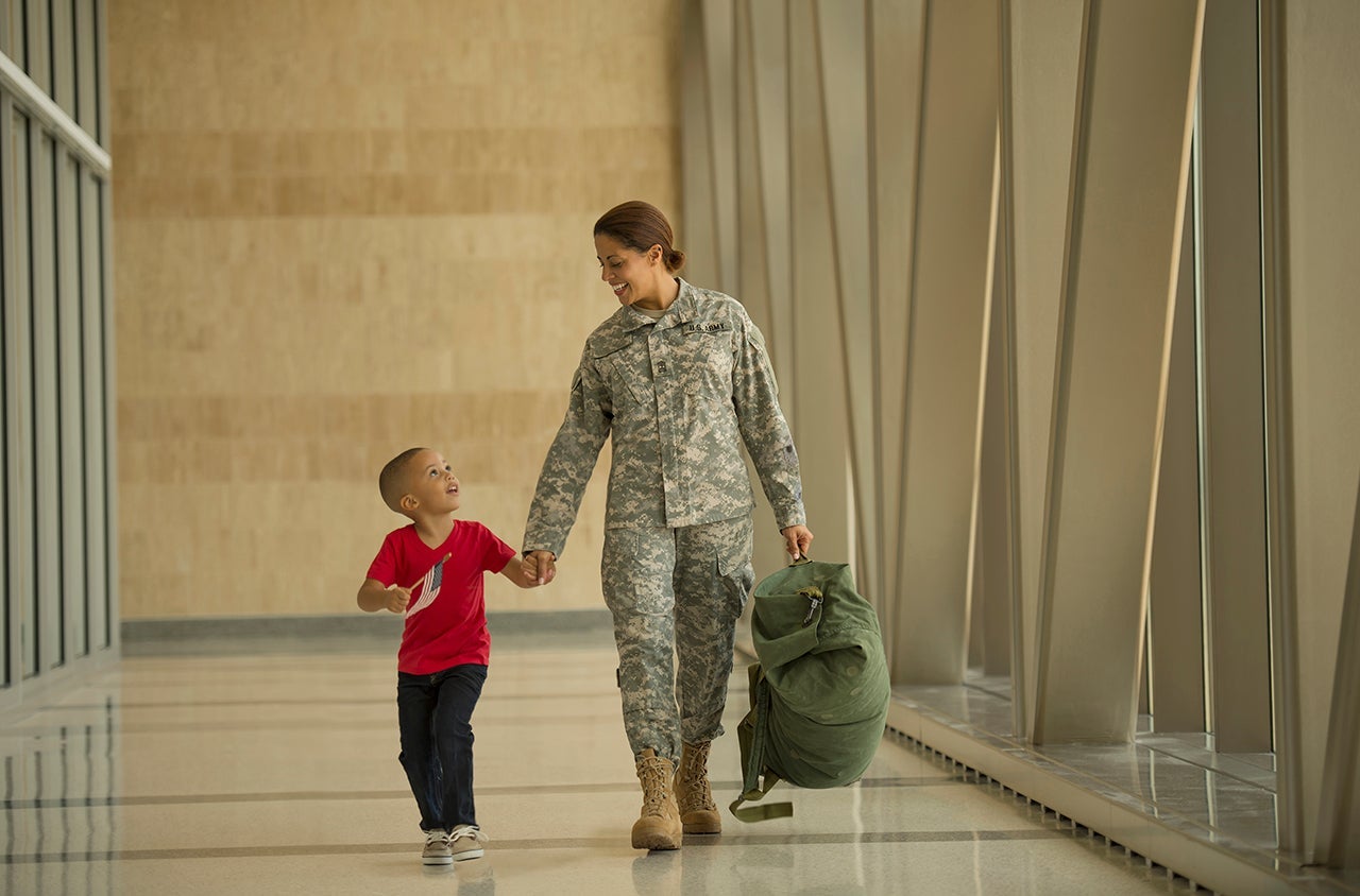 African American soldier and son walking in airport