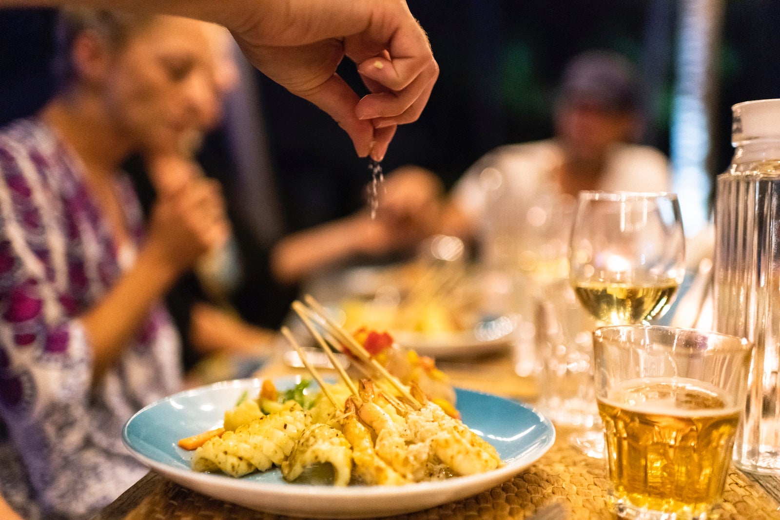 Sprinkling salt on fresh calamari and prawn skewers