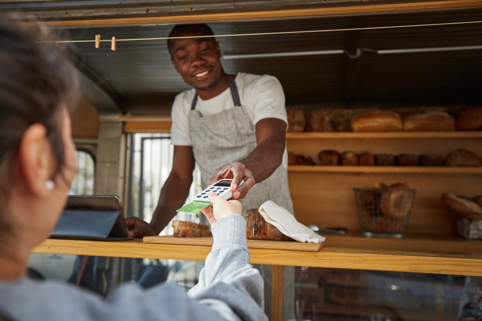 Woman with credit card paying salesman at food truck