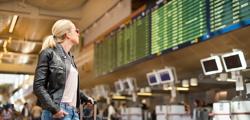 Woman looking at departure board delay cancel featured