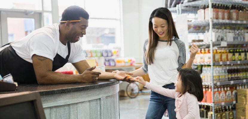 Deli worker giving mother and daughter cheese sample