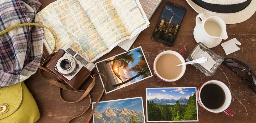 High angle view of coffee, maps, photographs, camera and cell phone