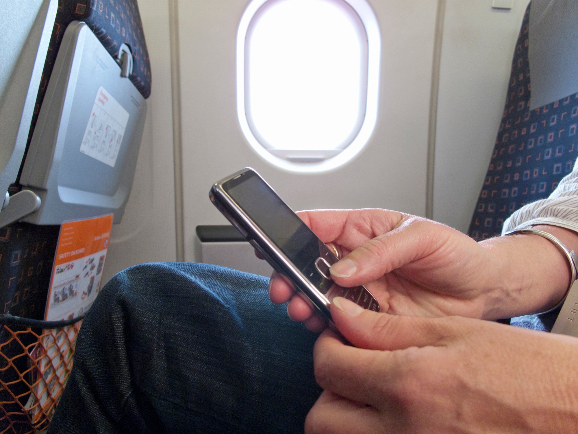 Close up of woman text messaging on cell phone in airplane
