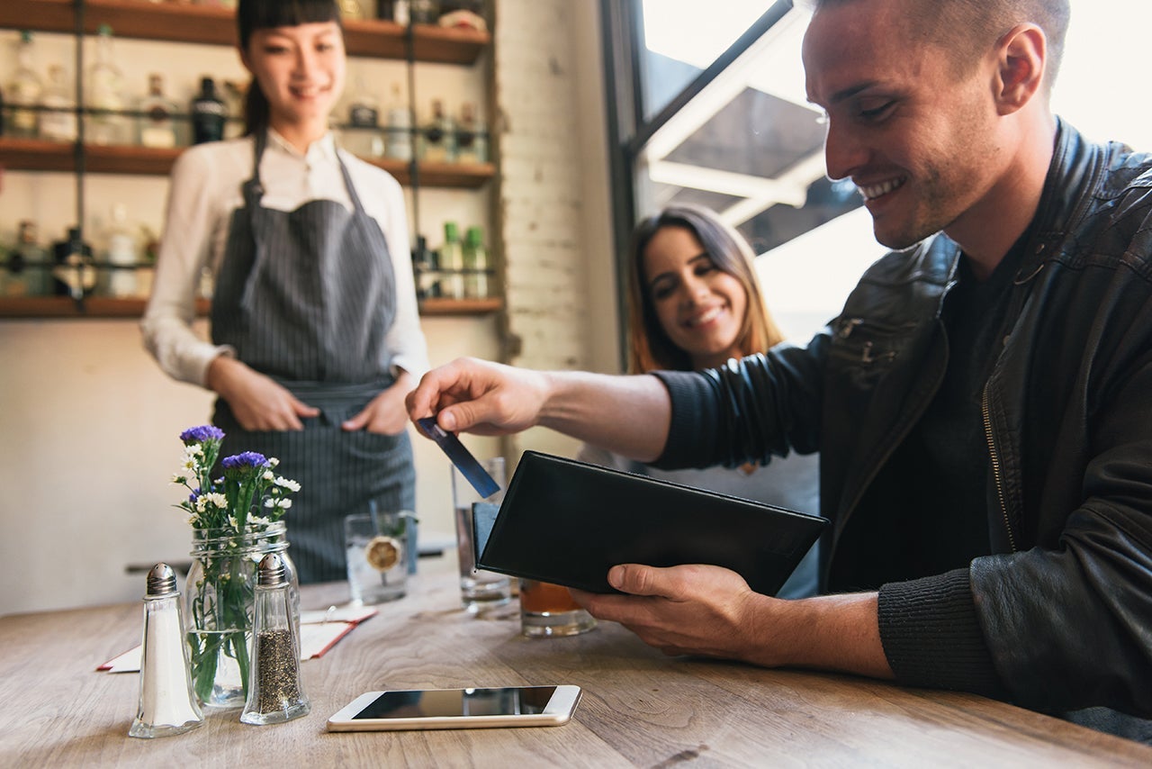 Young man paying with credit card in restaurant