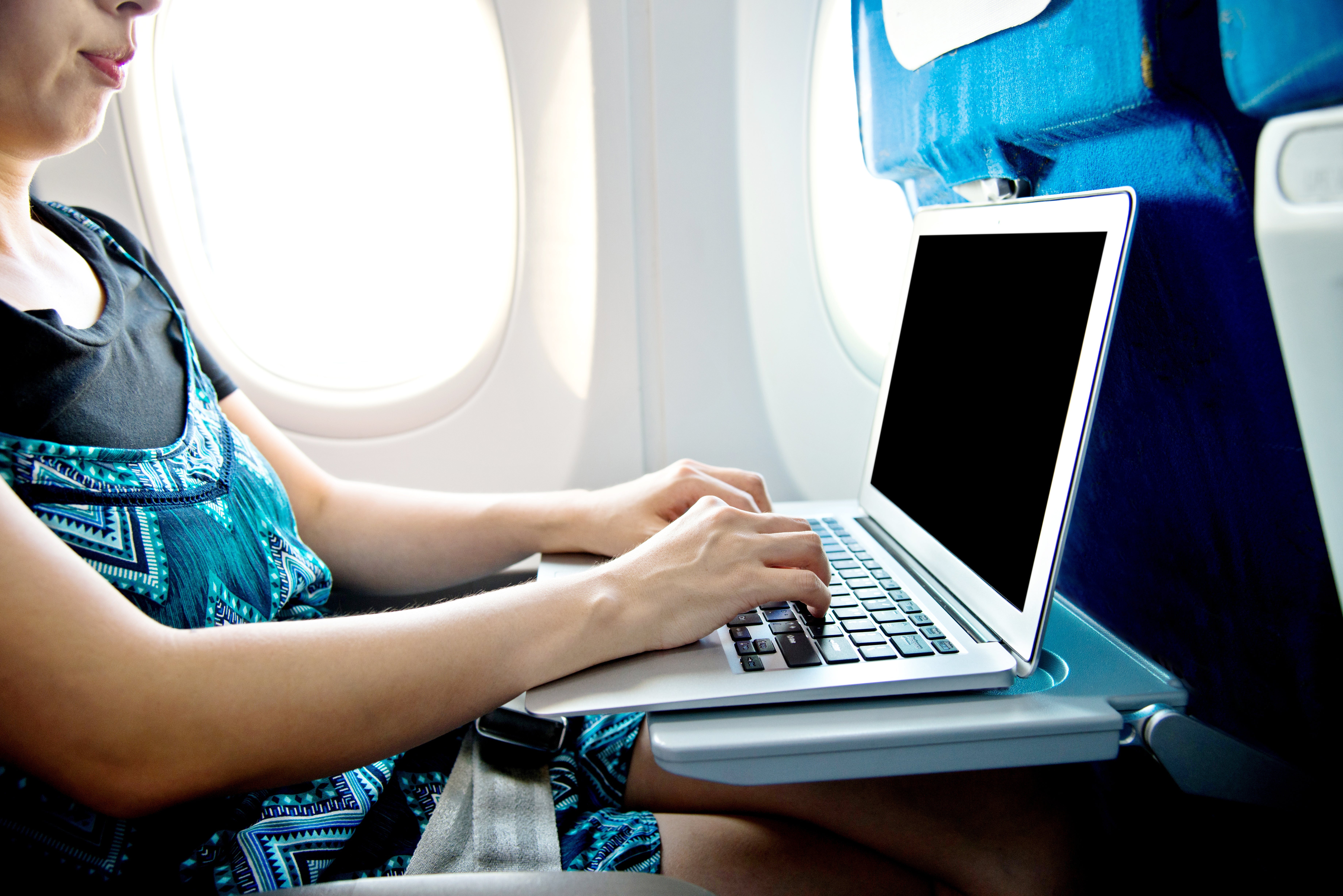 Woman using laptop computer on airplane
