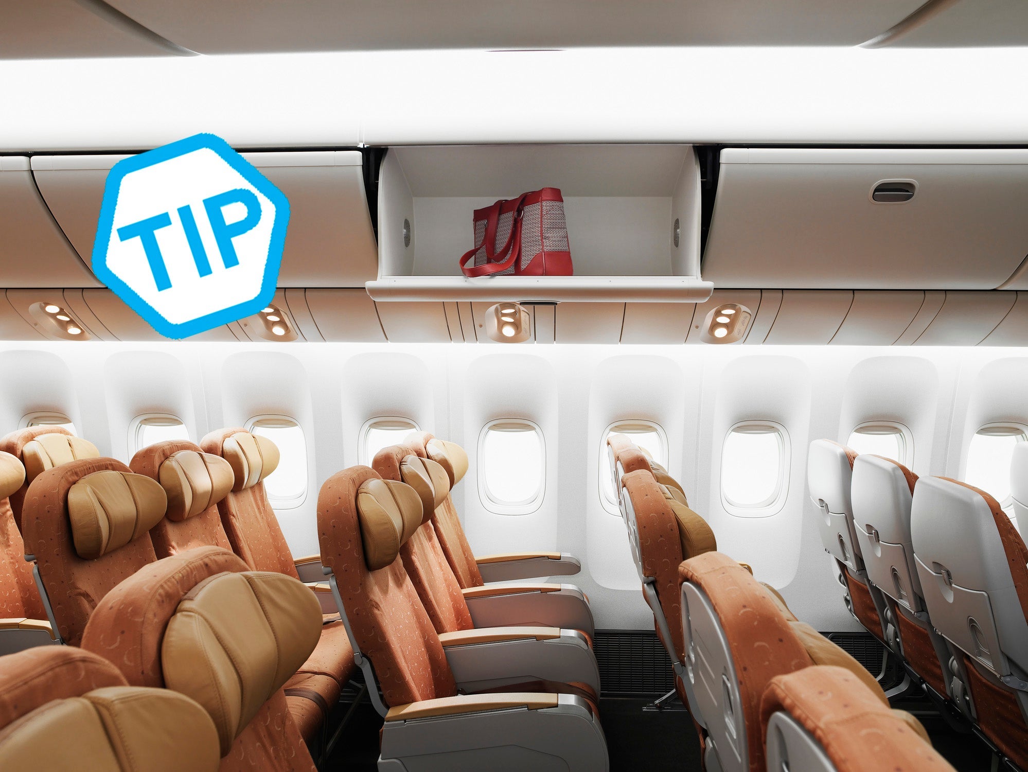 Empty airplane interior, bag left in overhead bin, side view