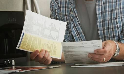 Hispanic man paying bills on laptop in kitchen