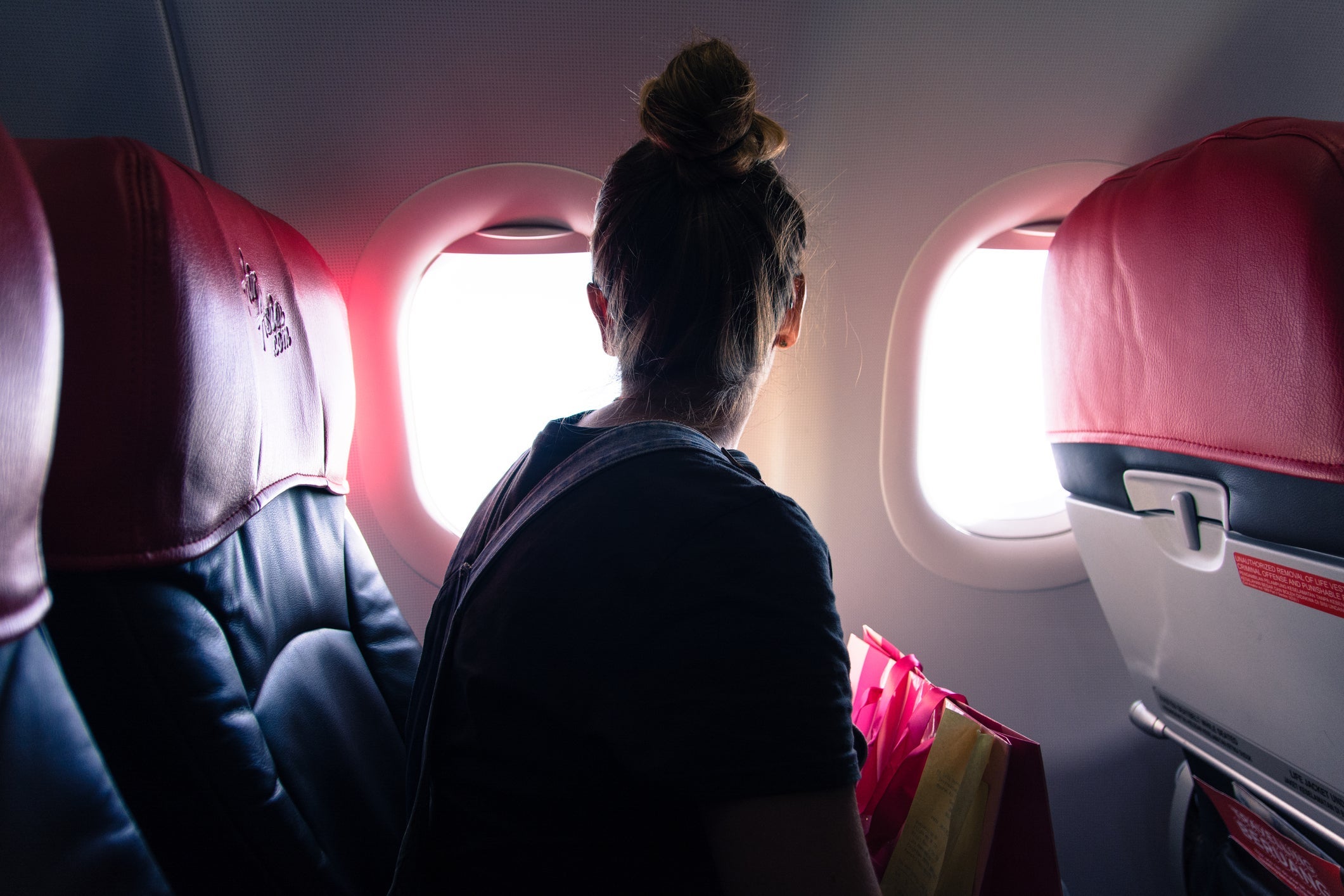Woman Looking Through Window While Traveling In Airplane