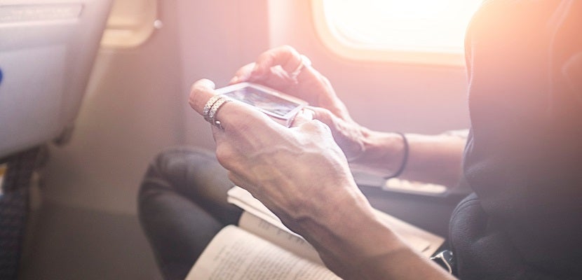 Person playing game on smartphone on board airplane