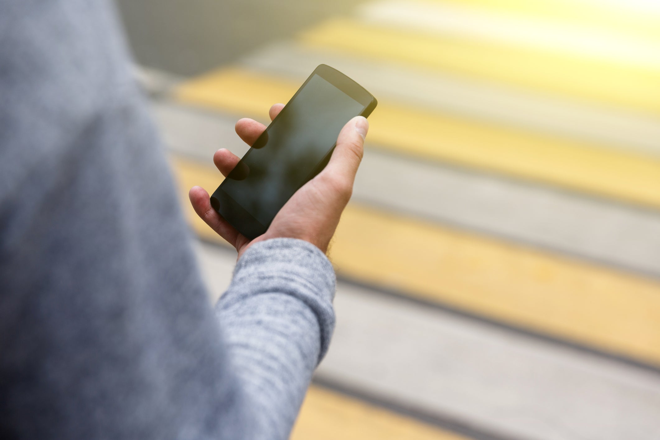 Closeup of mans hand holding phone with blank screen outdoors