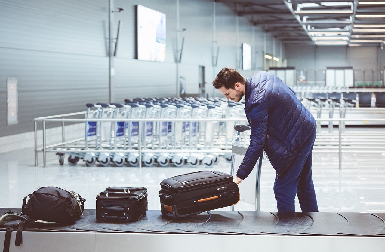 Young man picking luggage from conveyor belt in airport