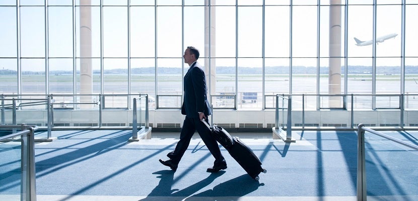 Caucasian businessman pulling luggage in airport