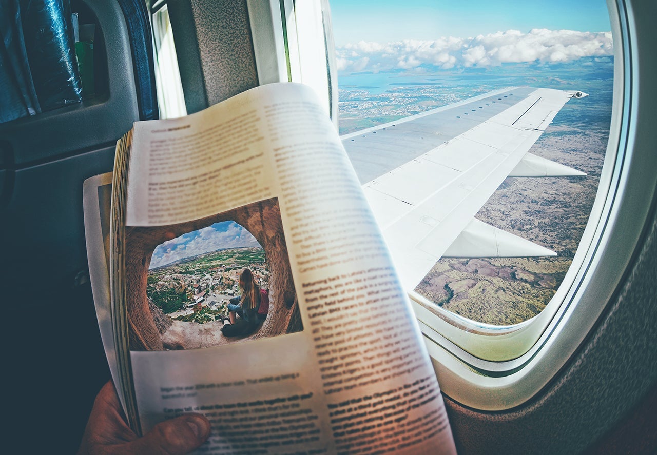Woman is sitting by window on a plane with magazine