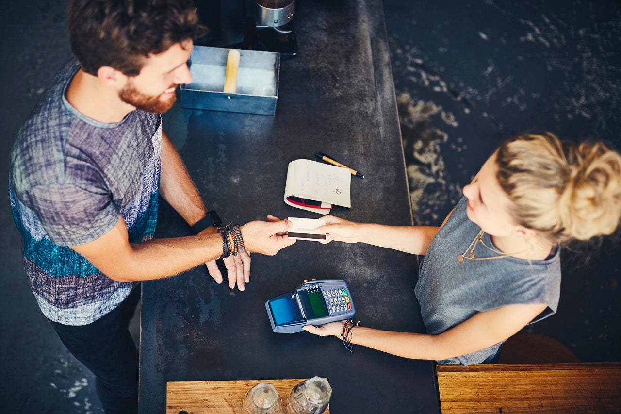 Cashier receiving credit card from man in cafe
