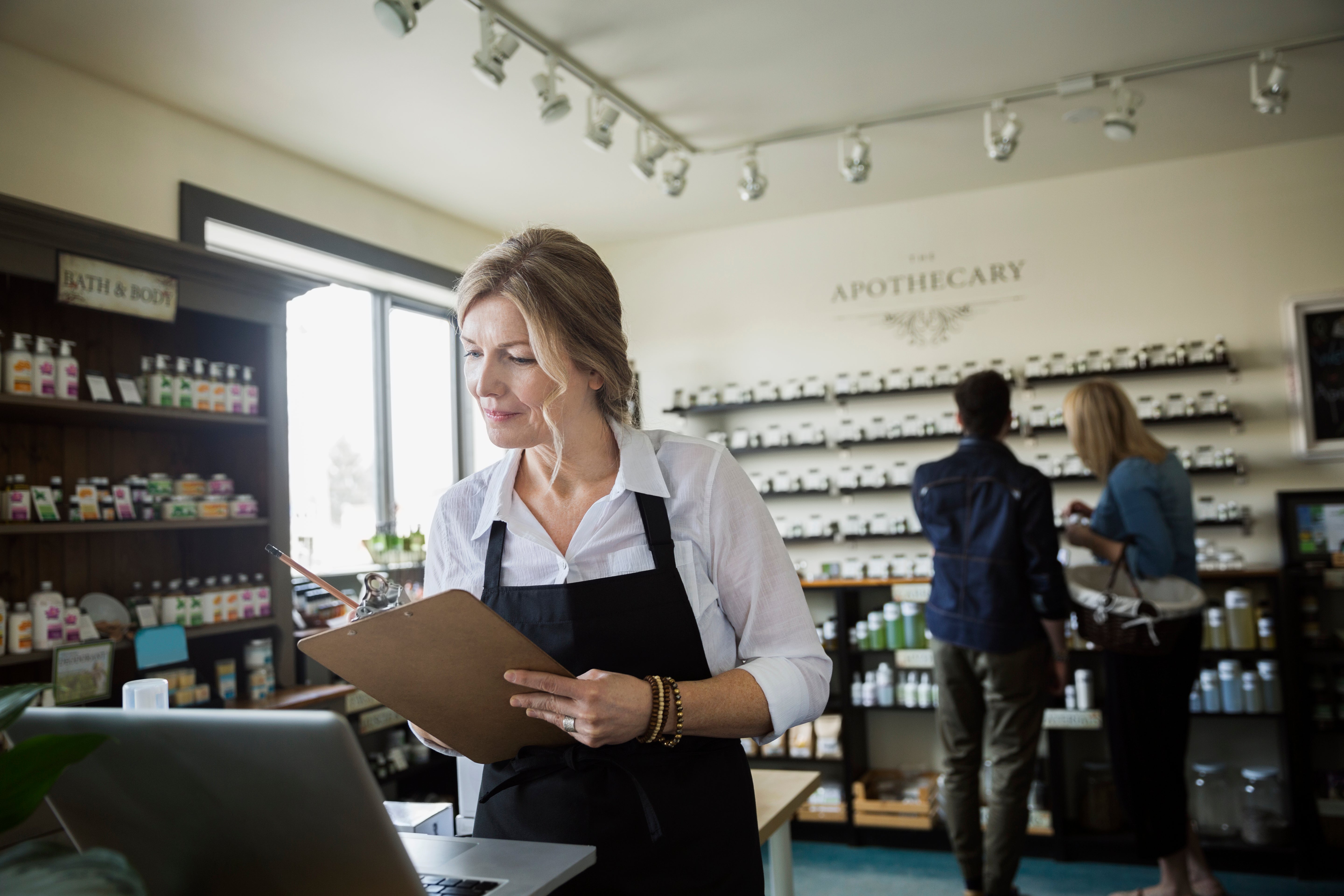 Apothecary shop owner checking inventory at laptop