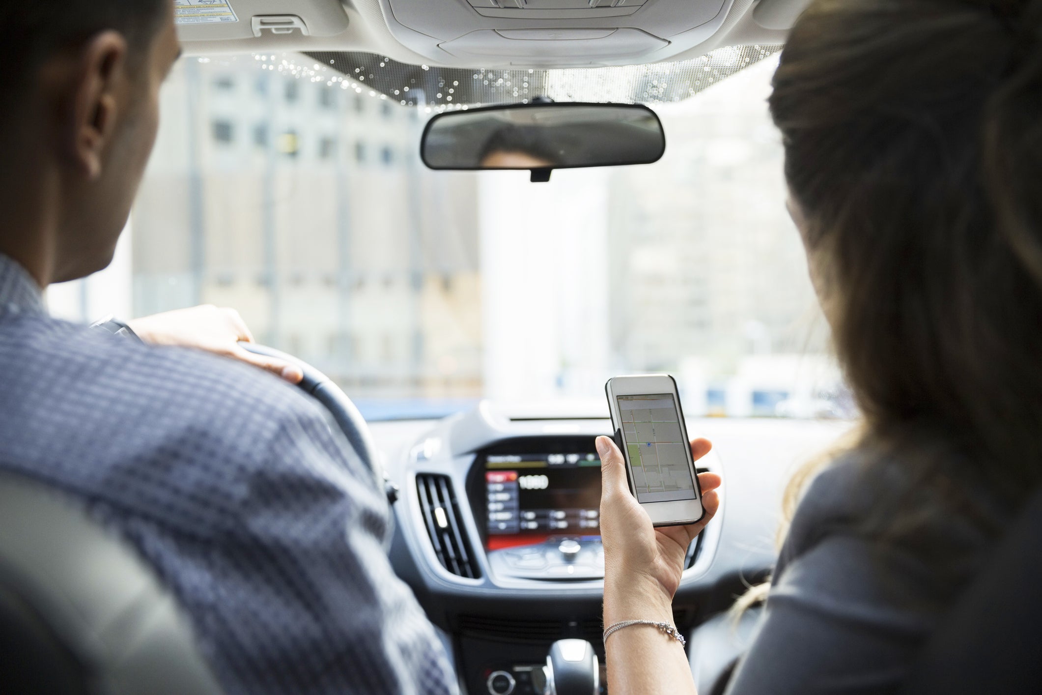 Businesswoman carpooling using cell phone in car