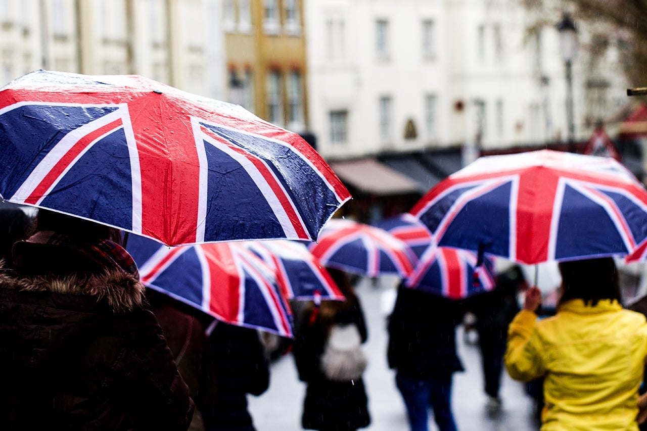Rear View Of People Walking On Road With Umbrella