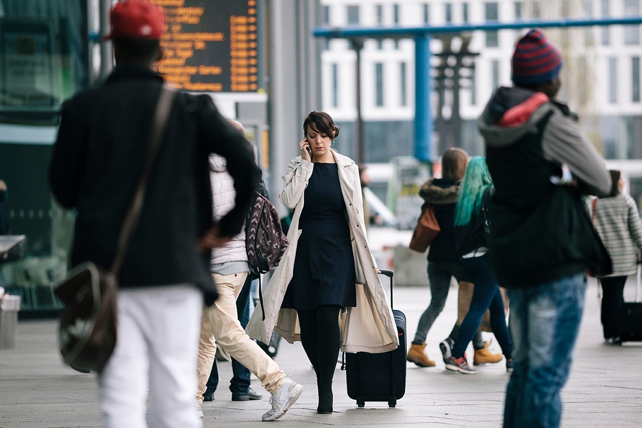 Businesswoman with suitcase using Smartphone