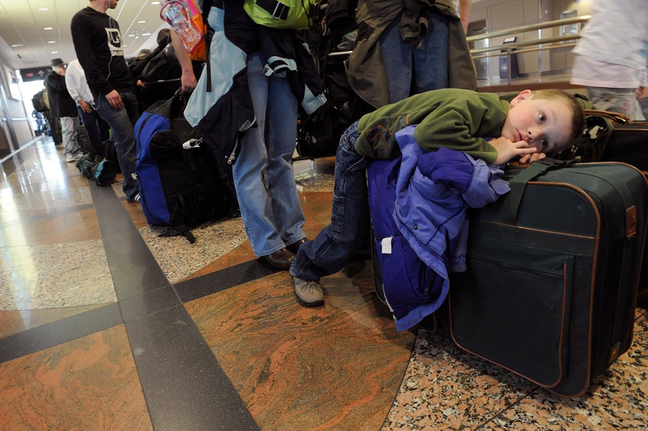 Child Waiting on Line in Airport with Suitcase