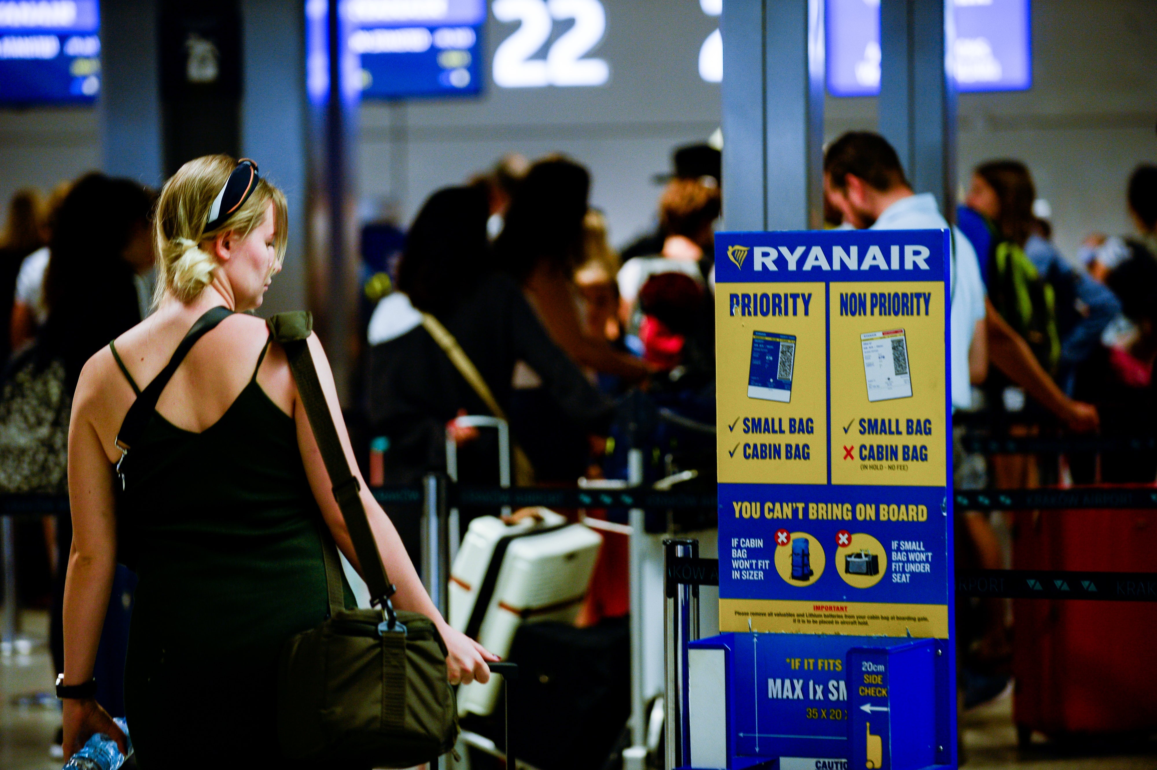 A woman passes by a Ryanair luggage info stand at Krakow
