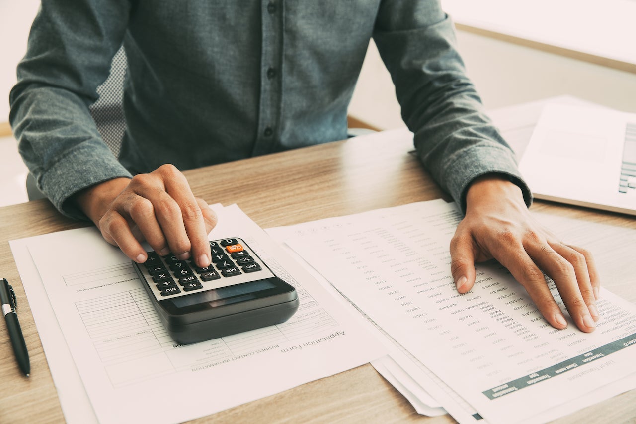 Accountant calculating income and examining report_tone