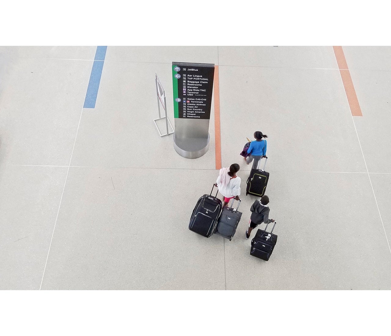a-black-family-walking-with-their-luggage-to-their-airport-terminal-as-seen-from-above_t20_Ky7vo1