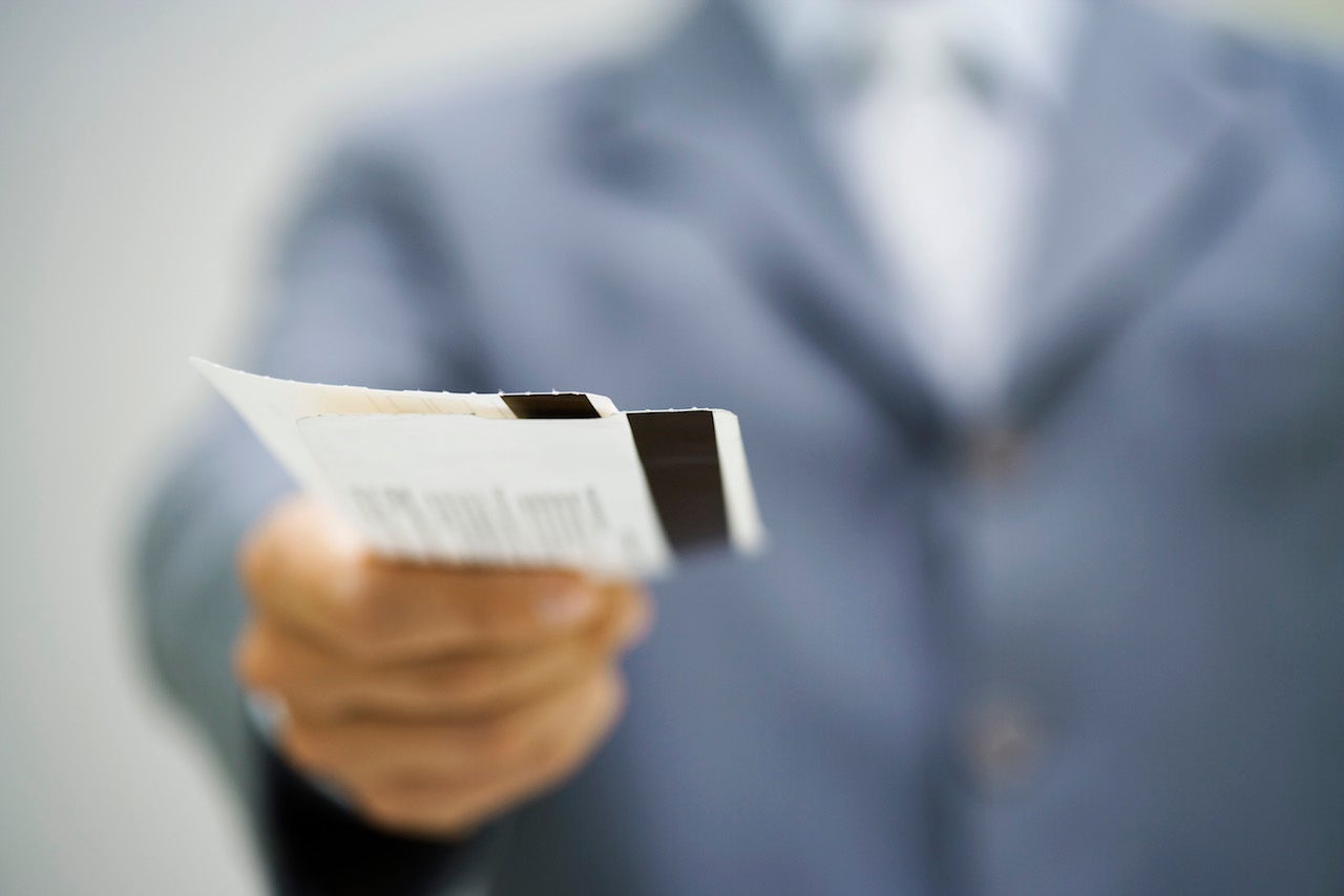 Man in suit holding out tickets