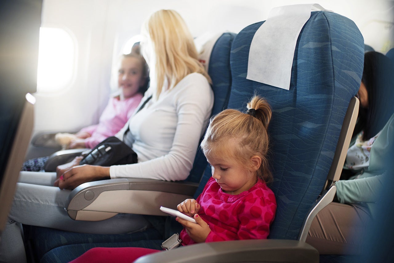 Little girl using smart phone in airplane.