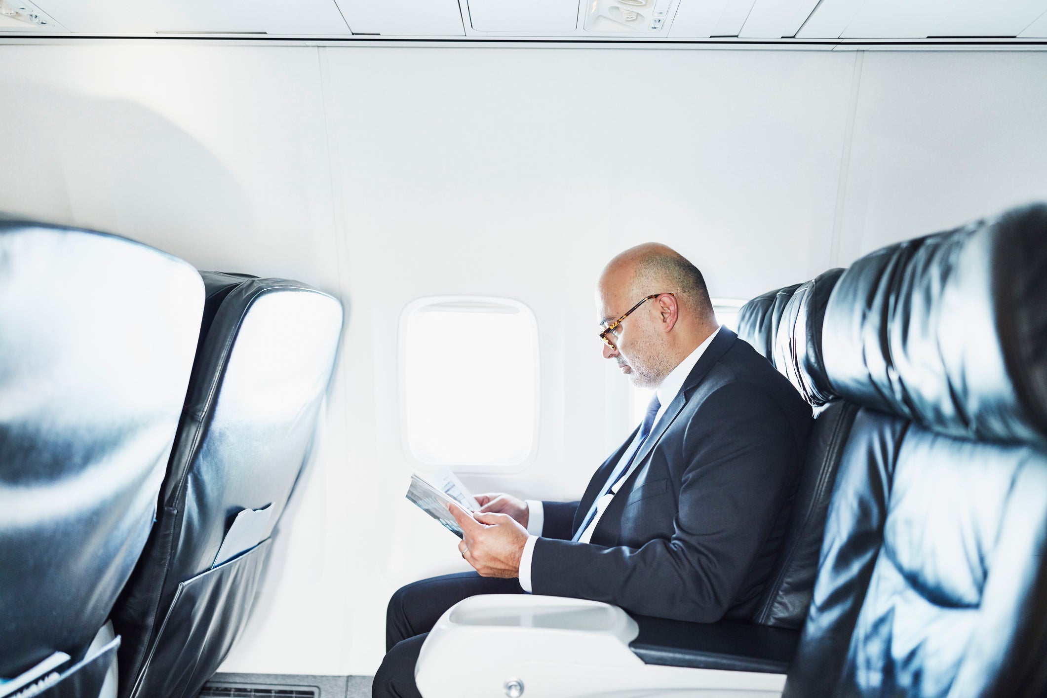 Businessman reading a magazine while traveling on airplane on business trip