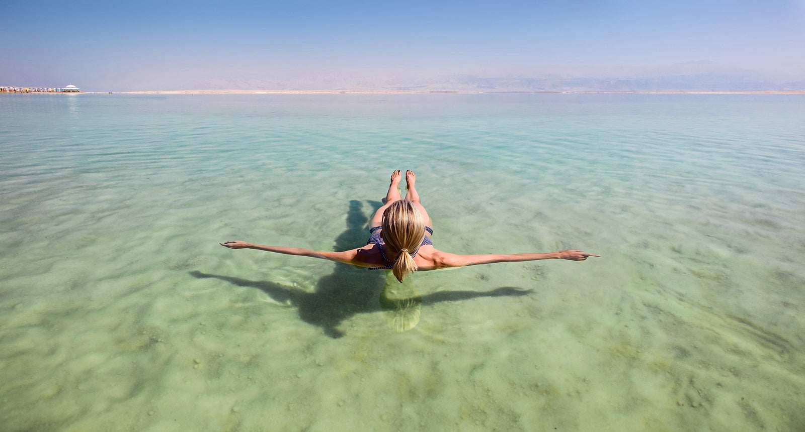 Blonde woman floating in the turquoise waters of the Dead Sea