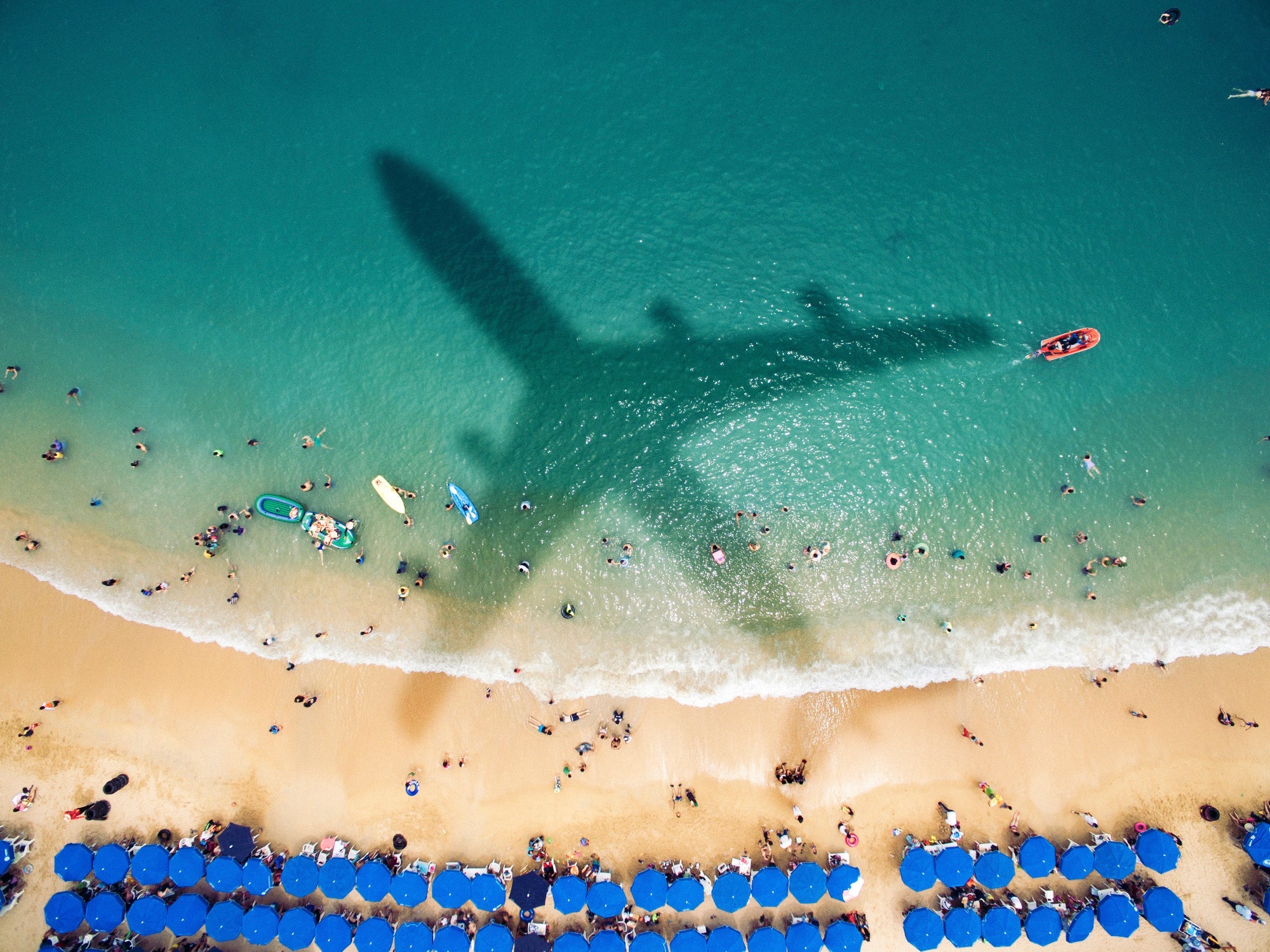 Airplane's shadow over a crowded beach