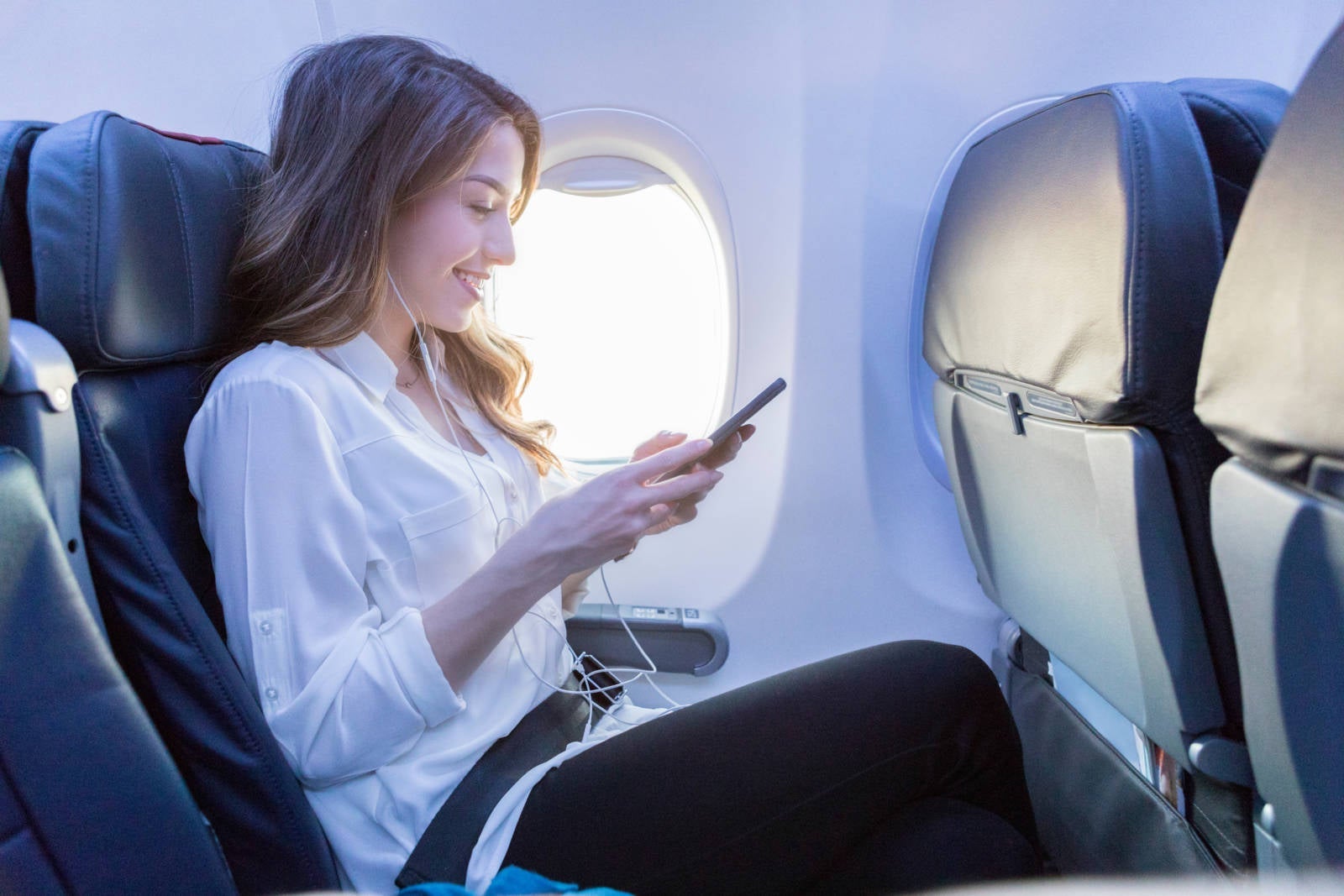 Young woman listens to music during air travel