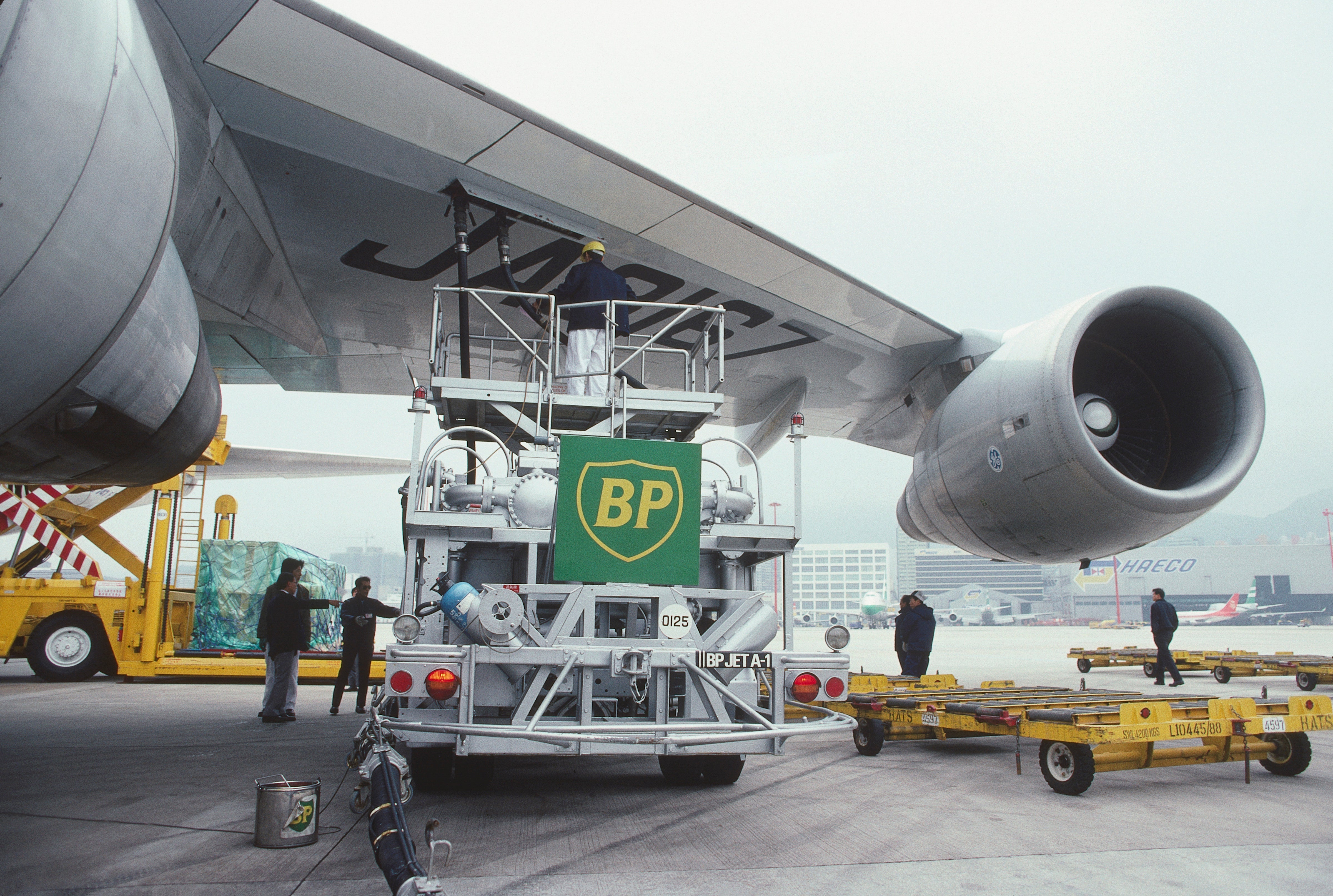 BP refuelling bowser under wing and a GE CF-6-50E2 engine intake of a Nippon Cargo Airlines Boeing 747-200F with cargo being loaded behind