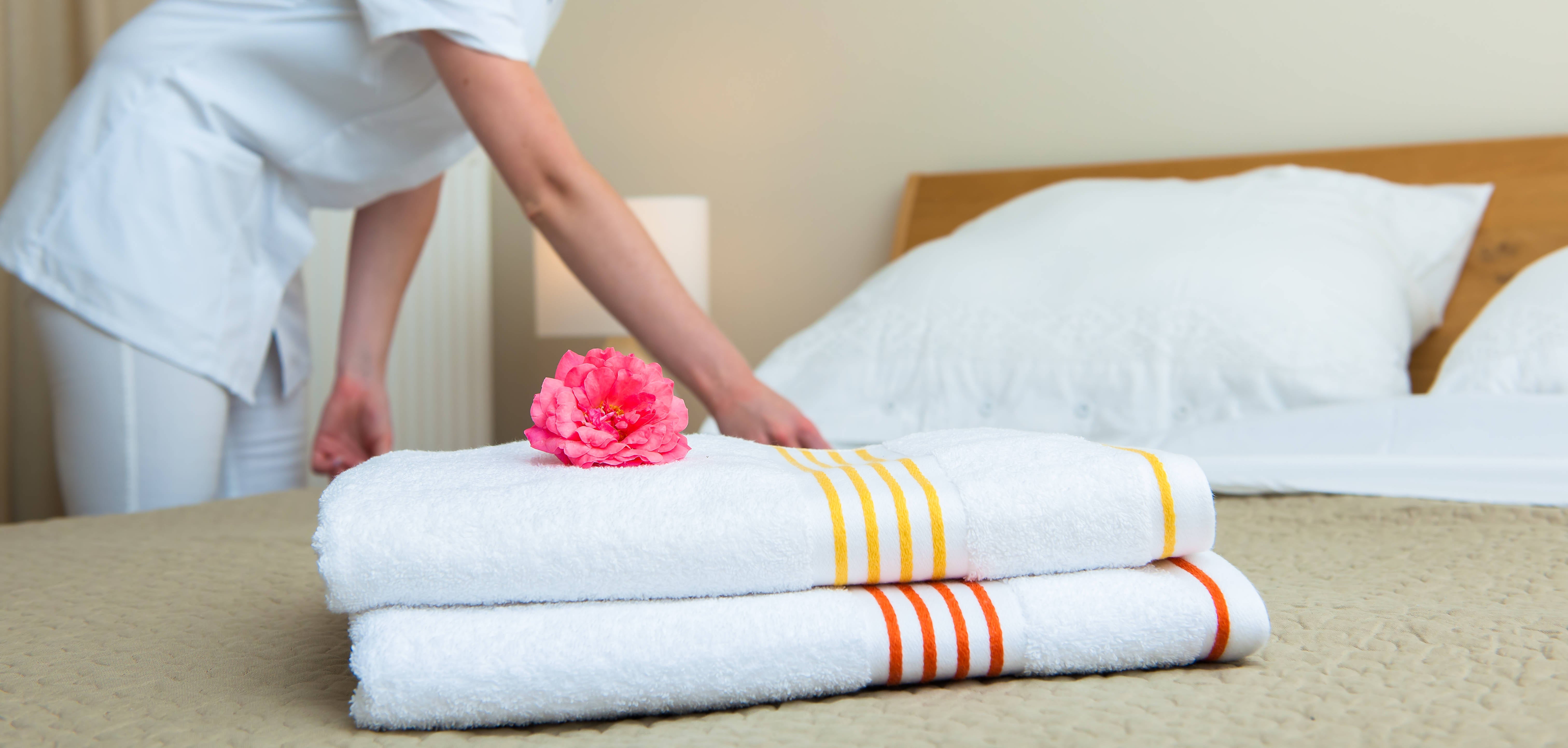 Maid making bed in hotel room