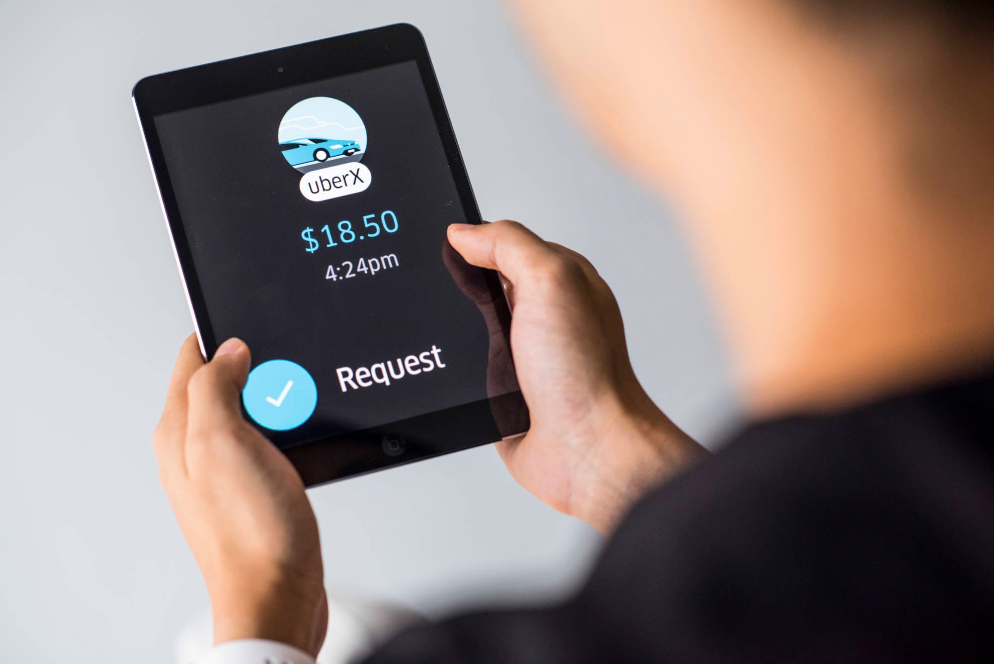 Young man holds a smart device while using Uber app