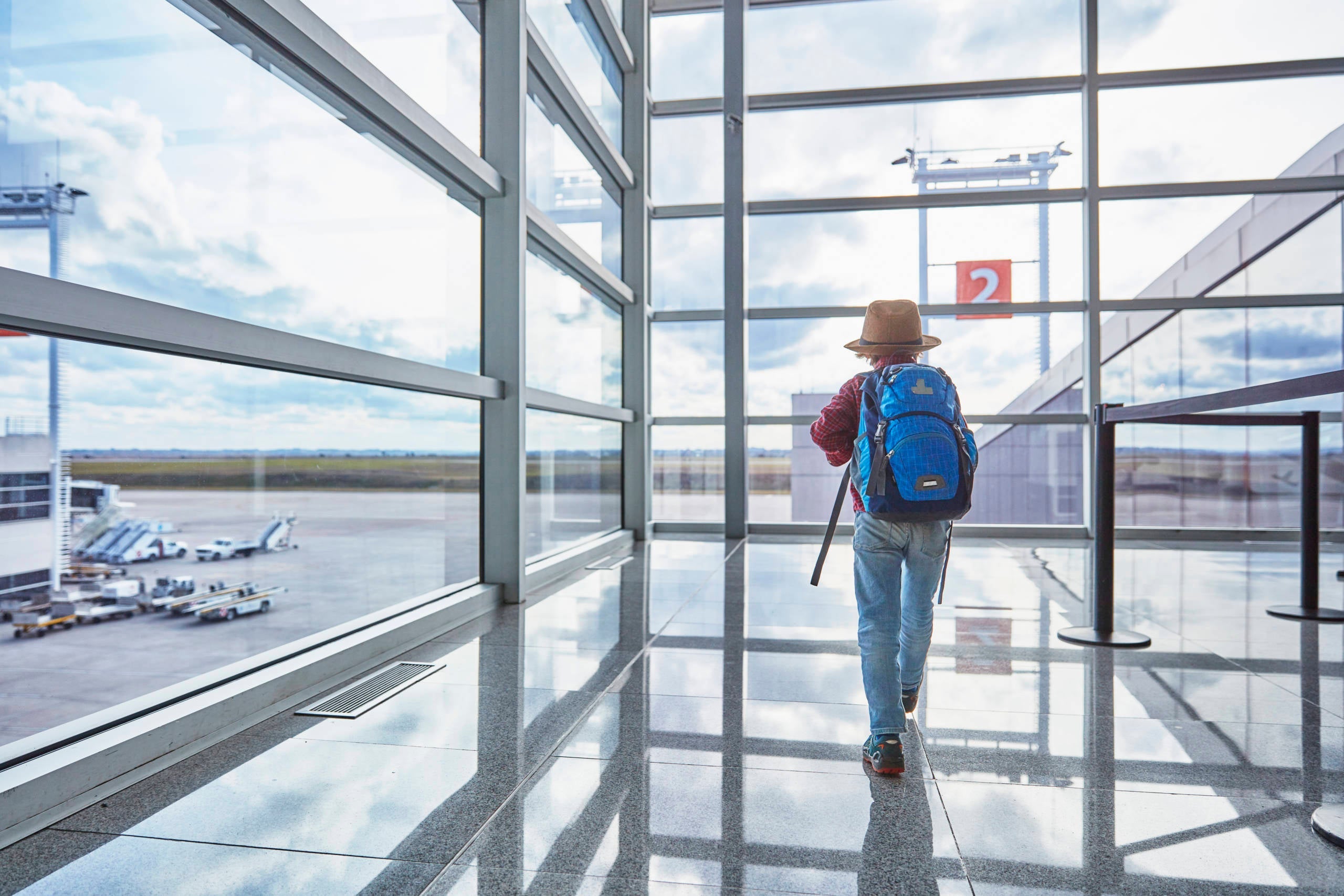 Boy with backpack at the airport running towards departure gate
