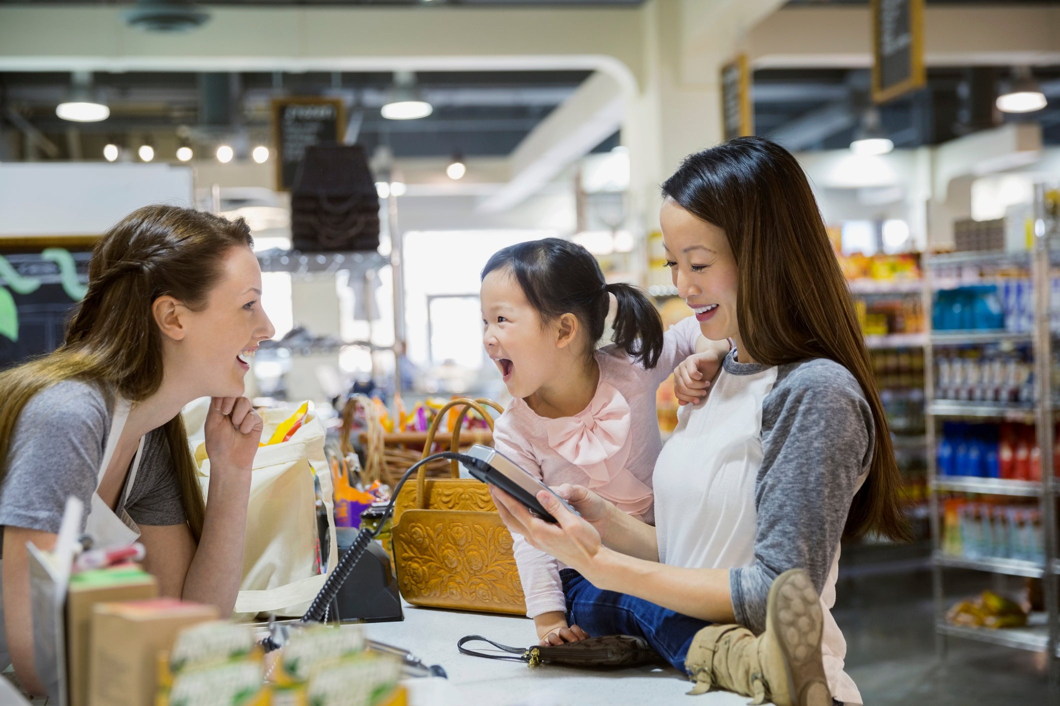 Mother and daughter paying at grocery store checkout