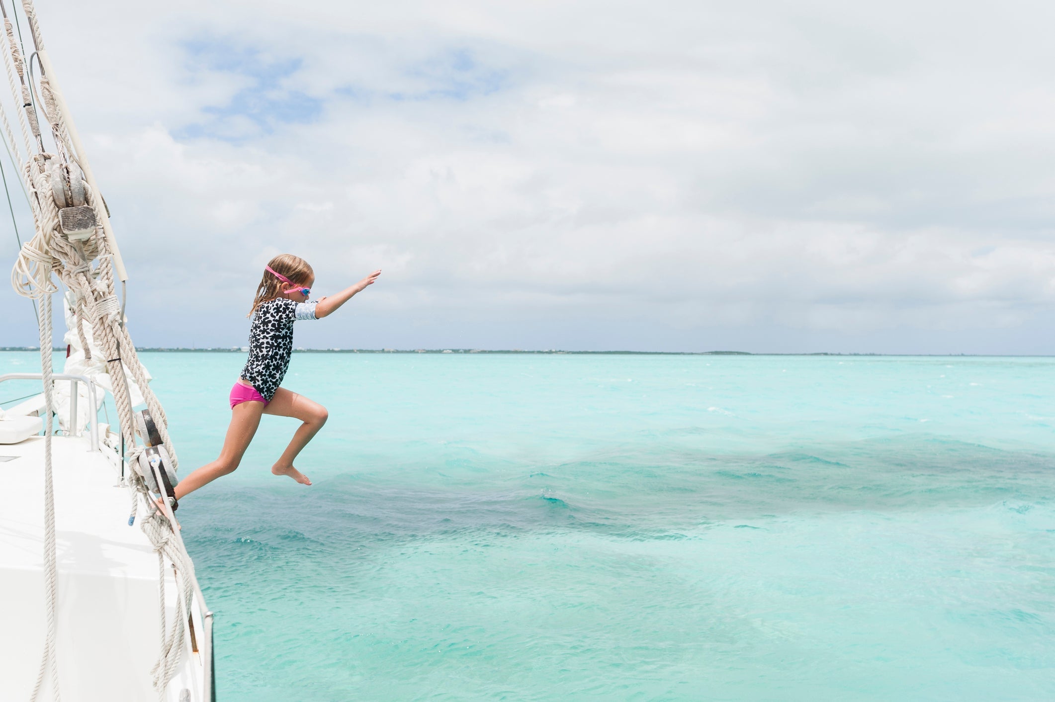Full length of girl diving in sea from boat against cloudy sky