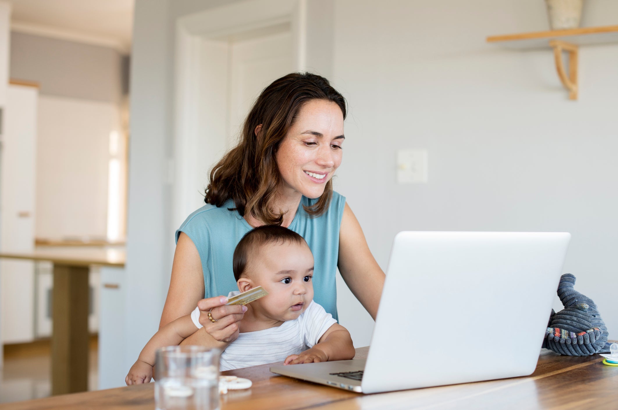 Woman with baby boy online shopping while using laptop computer at home