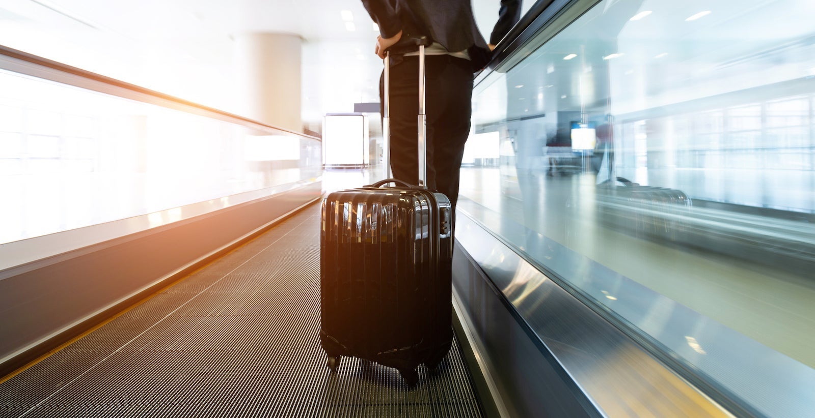 Businesswoman at moving sidewalk, taking way to the departure gate