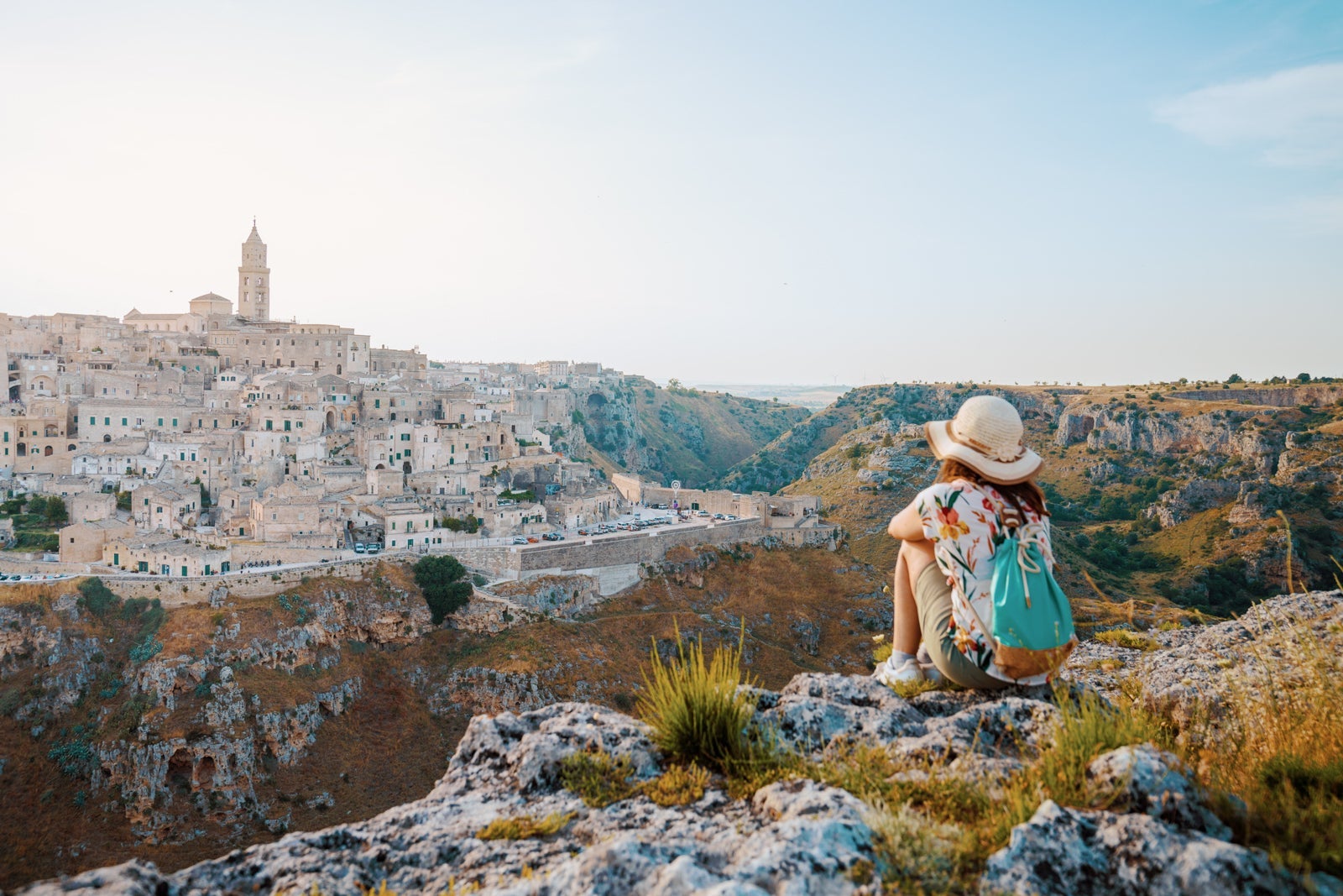 Woman tourist admiring the view of Matera at sunset. Murgia Belvedere, Basilicata, Italy