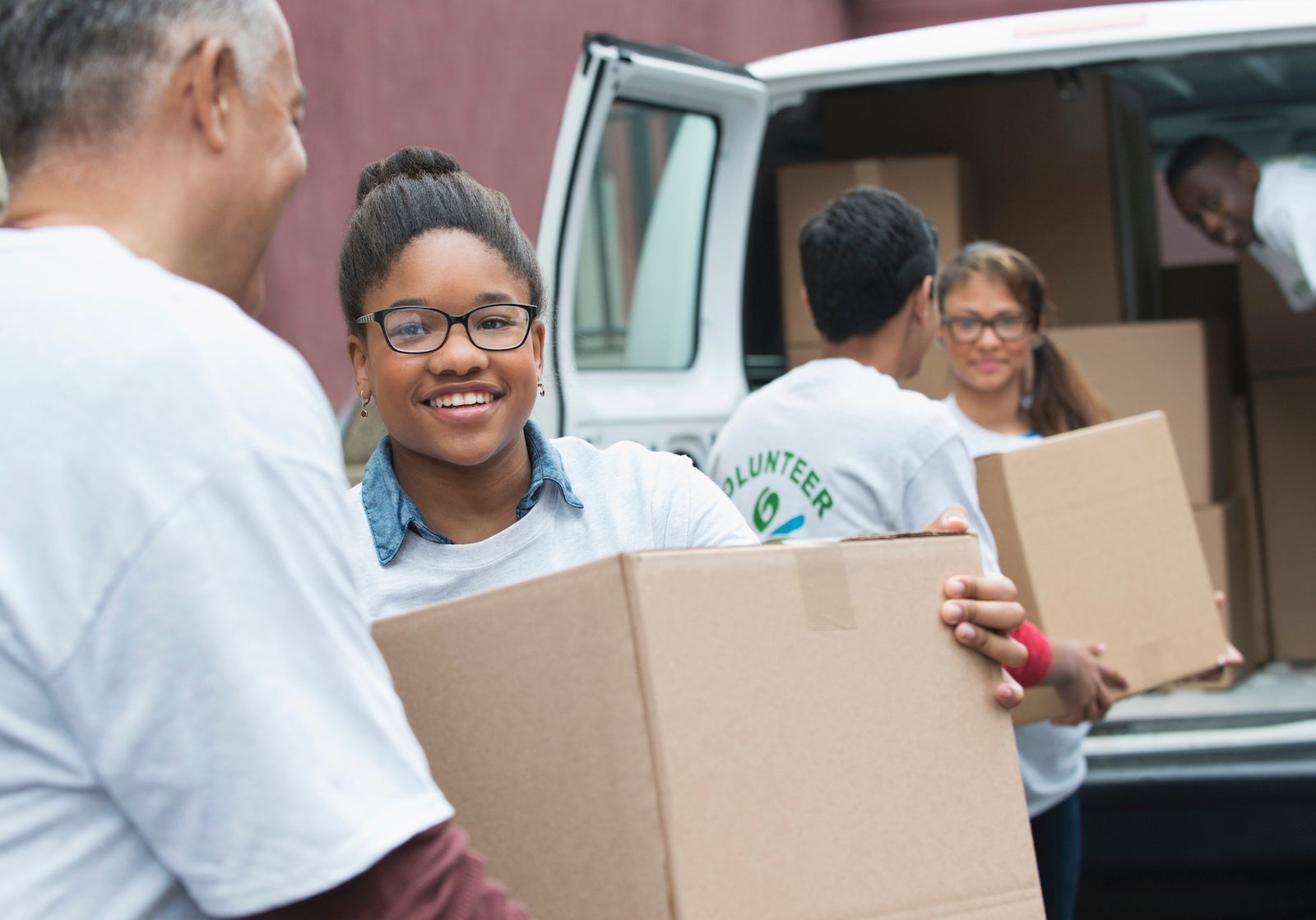 Volunteers passing cardboard boxes from delivery van