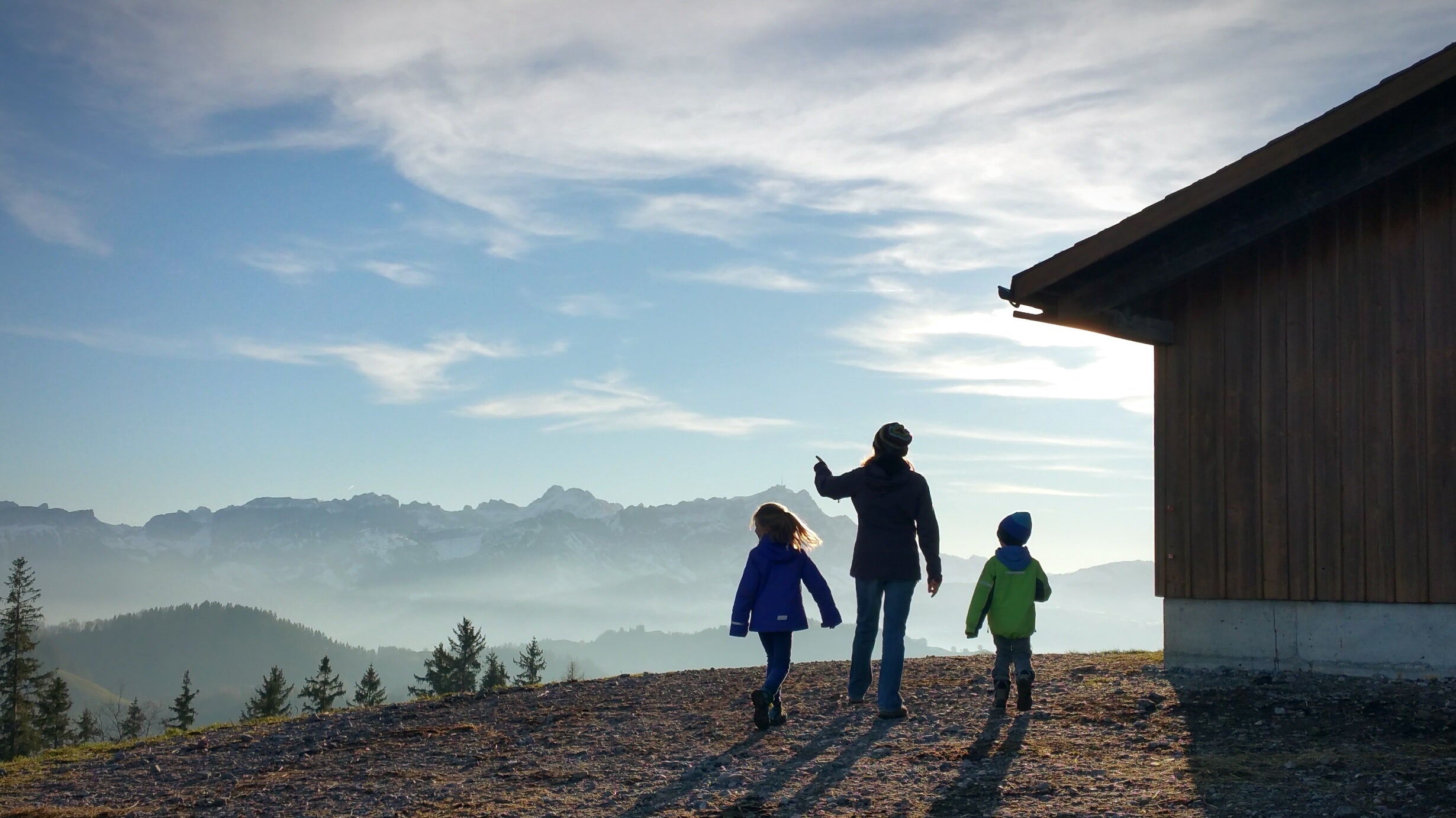 Rear View Of Mother And Children Standing On Hill Against Sky During Foggy Weather