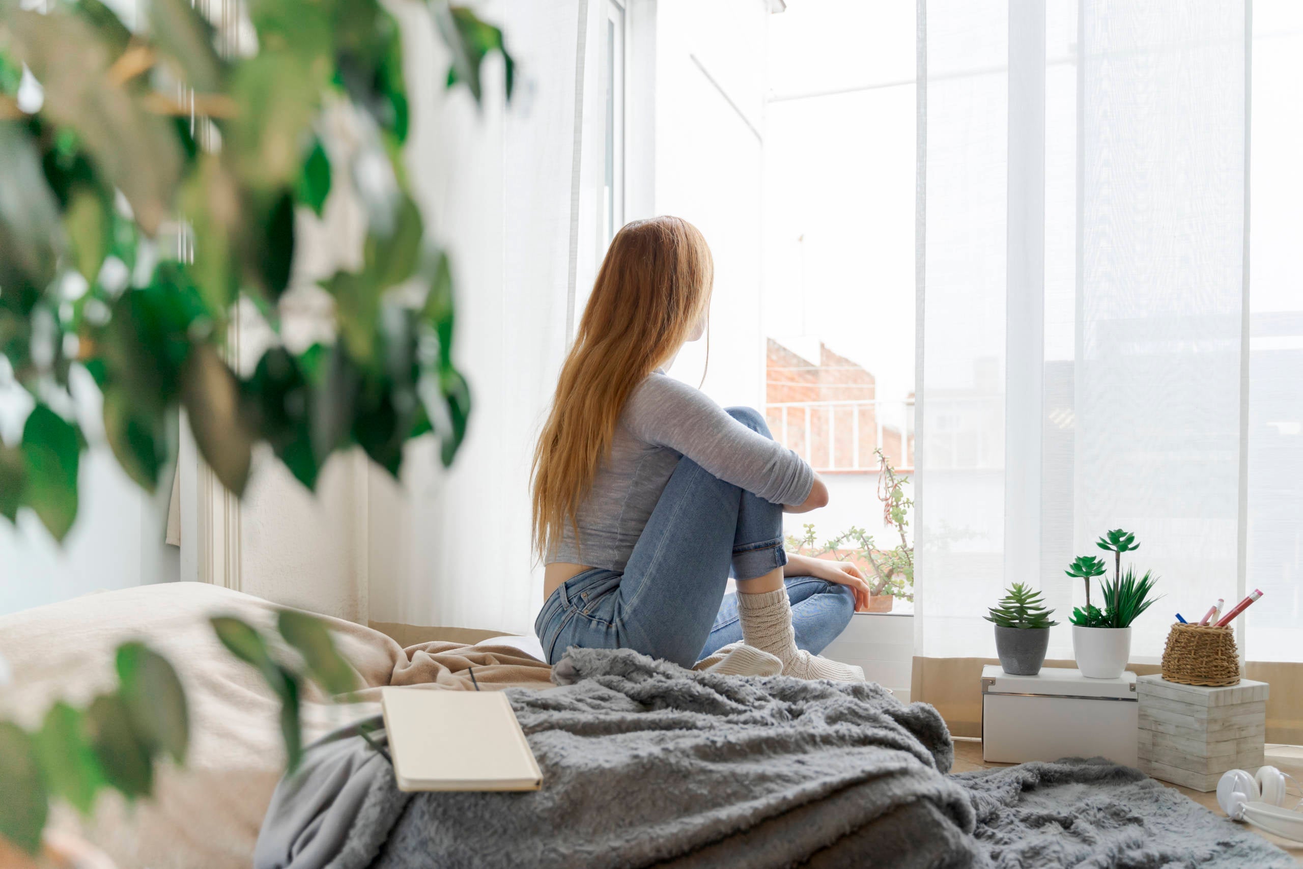 Young woman at home looking out of window