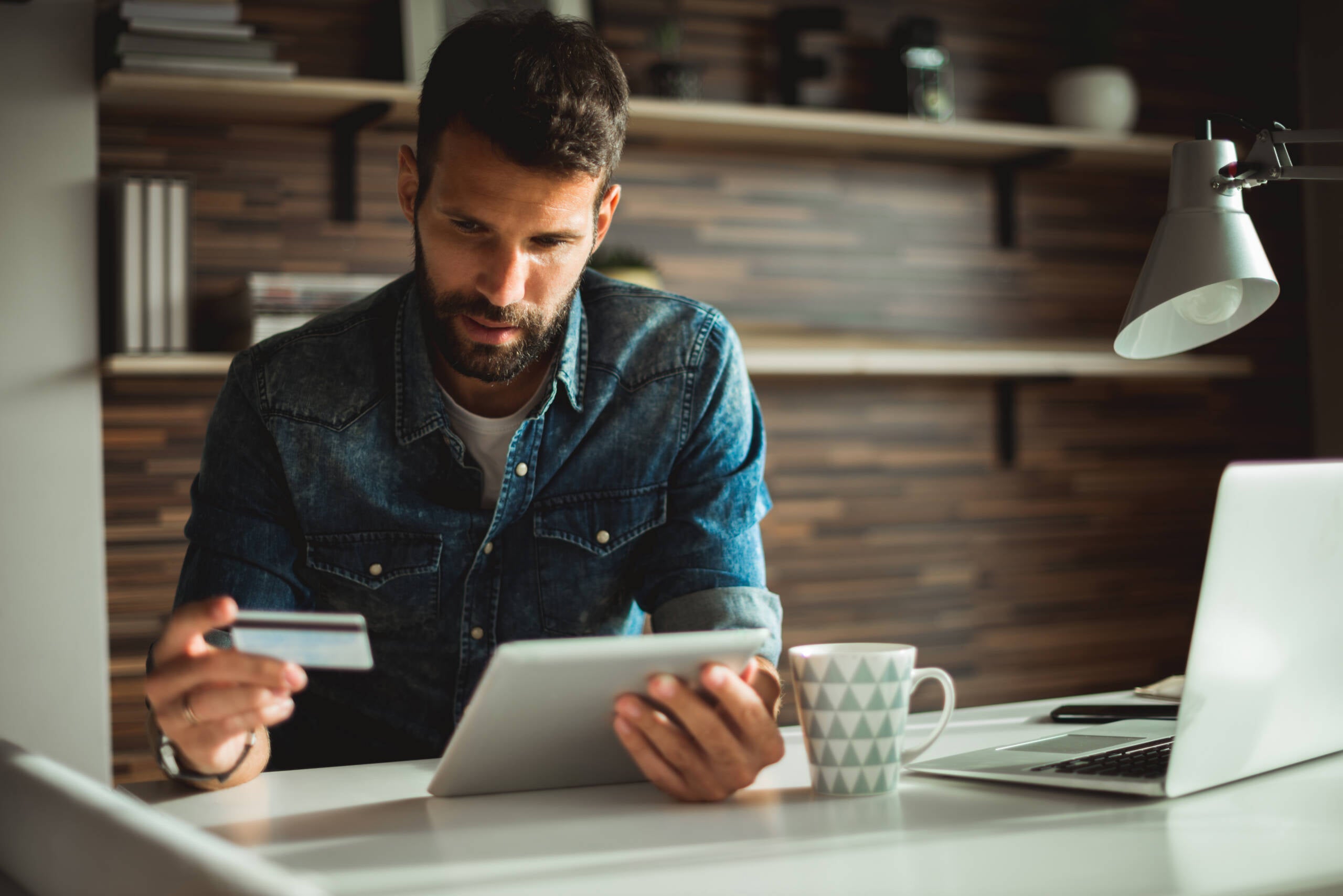 Man holding credit card while using digital tablet in the office.