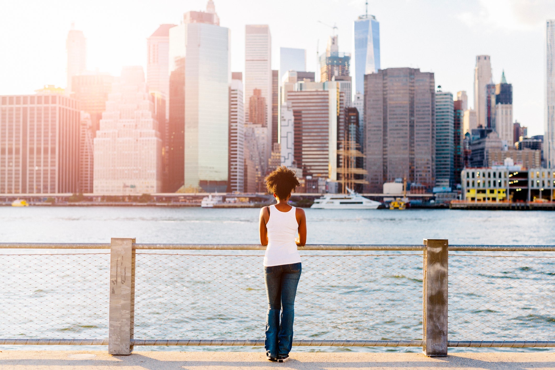 USA, New York City, Brooklyn, woman standing at the waterfront looking at the skyline
