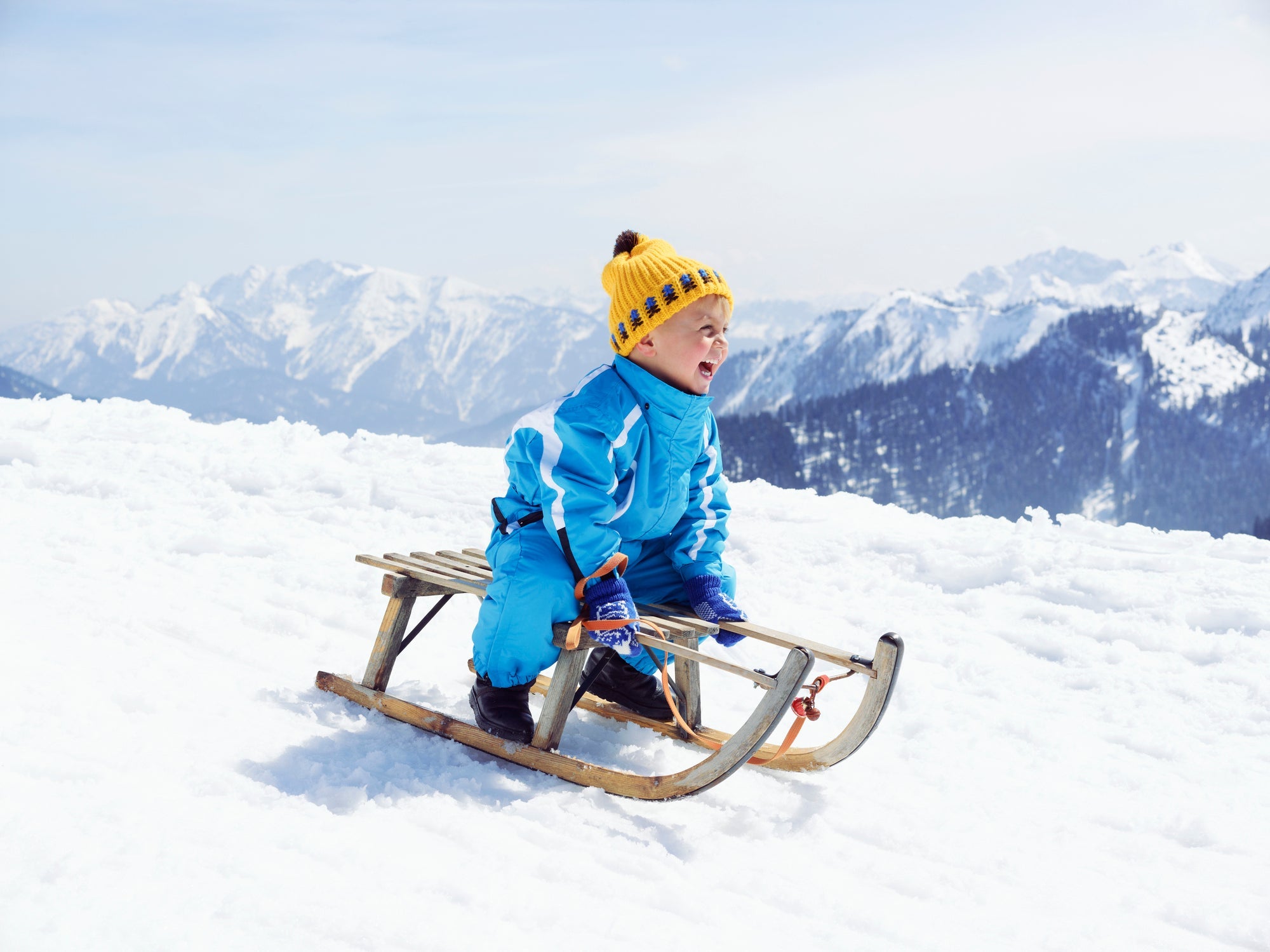 Germany, Tegernsee, Wallberg, smiling little boy sitting on sledge